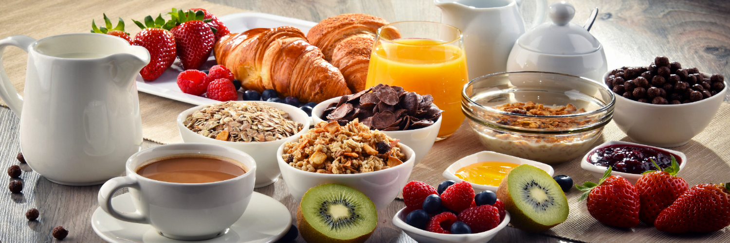 Bild vom Frühstück mit frischem Obst, Kaffee und Croissants sowie Müsli und andere Köstlichkeiten.